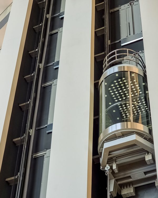 glass capsule elevator ,lift at luxury hotel or building.modern glass elevator to the upper floors, high building ,office and shopping mall glass capsule elevator with people or tourist in the lift on vintage wall in the hall at luxury hotel or building