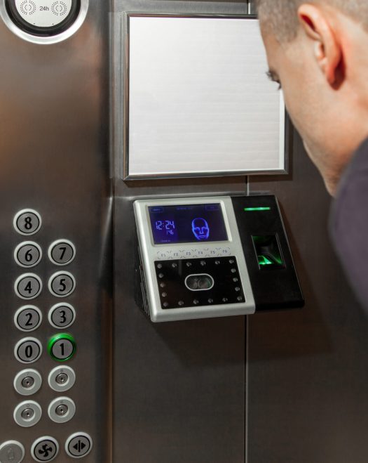 A man shows his face to a fingerprint access control terminal with a facial recognition function installed in the elevator A man shows his face to a fingerprint access control terminal with a facial recognition function installed in the elevator of a business center.